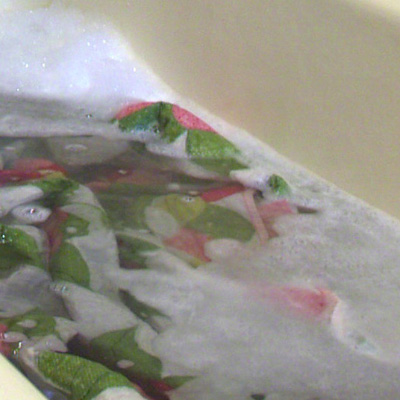 Picture of a ivy and rose colored quilt being professionally washed in soapy water.